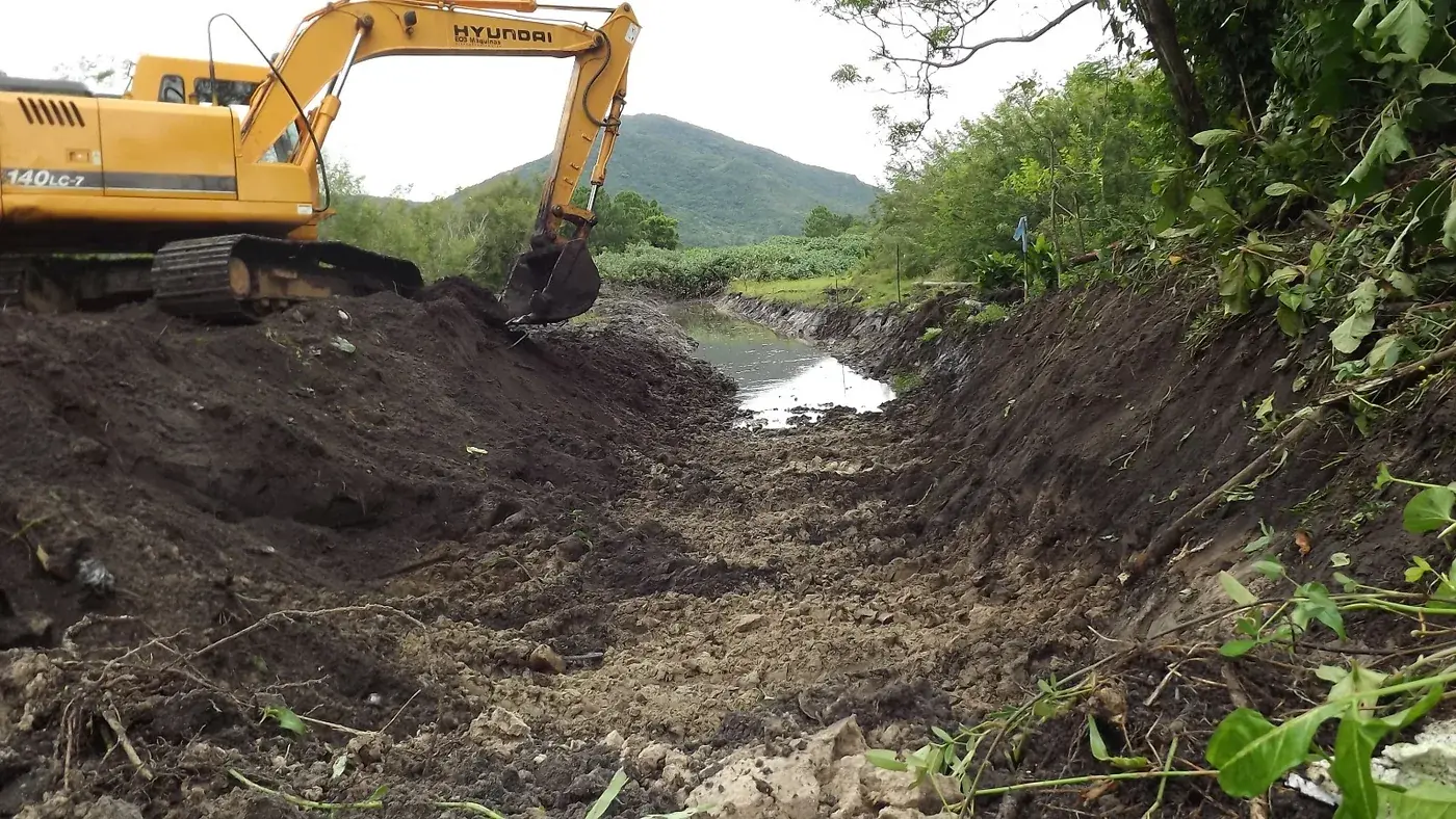 Escavadeira abrindo vala de contenção em área de mata durante atendimento emergencial de vazamento de óleo em subestação da Celesc, em Florianópolis